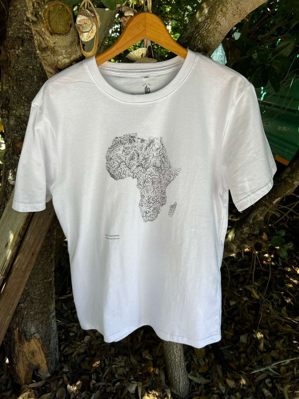 A white T-shirt hangingn on a tree with in black a map of Africa showing the rivers